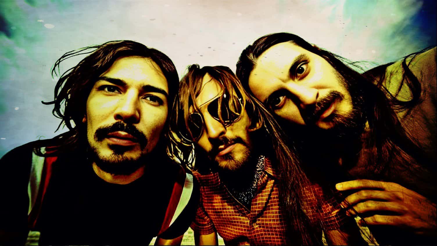 Vivid close-up of three rock band members with long hair and expressive faces, capturing the essence of music history and culture highlighted in the Past Daily sound archive.