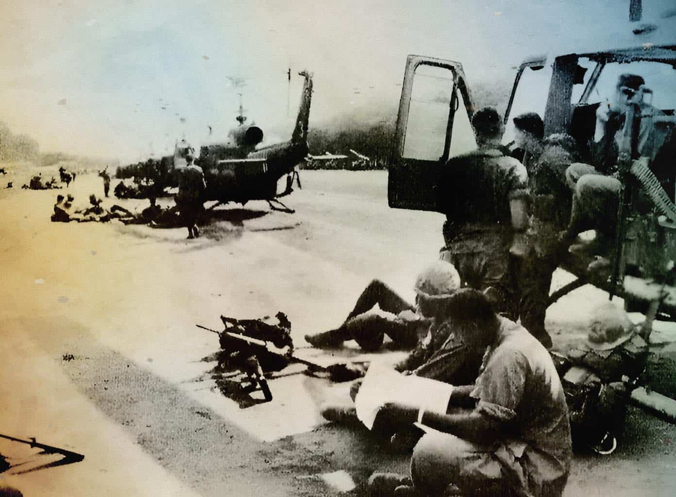 A historical black and white photo of soldiers and civilians around military helicopters during a wartime scene. The image captures conflict, military operations, and the human impact of war, highlighting the significance of historical news and events.