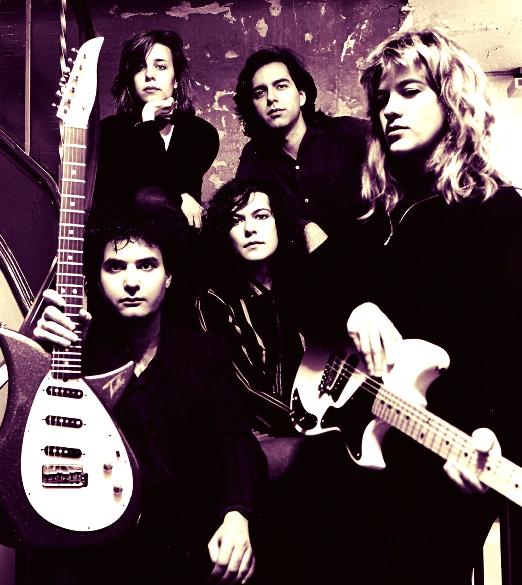 Bold black and white photo of a rock band with five members holding electric guitars, showcasing music history and legendary musicians, emphasizing vintage music archive content.