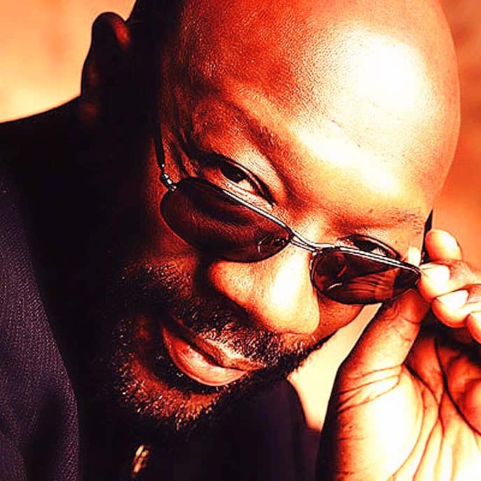 Cool man with sunglasses, close-up portrait, confident expression, bald head, stylish and modern look perfect for music and cultural history themes.