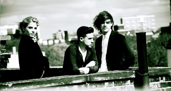 Three young people standing on a rooftop, capturing a vintage or retro vibe with urban background, representing music, youth culture, and historical fashion.