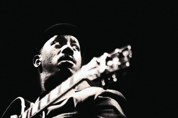 Harold Melvin playing guitar, iconic black and white photo, jazz and blues music history, vintage music artist, black musician portrait, Past Daily archive image.