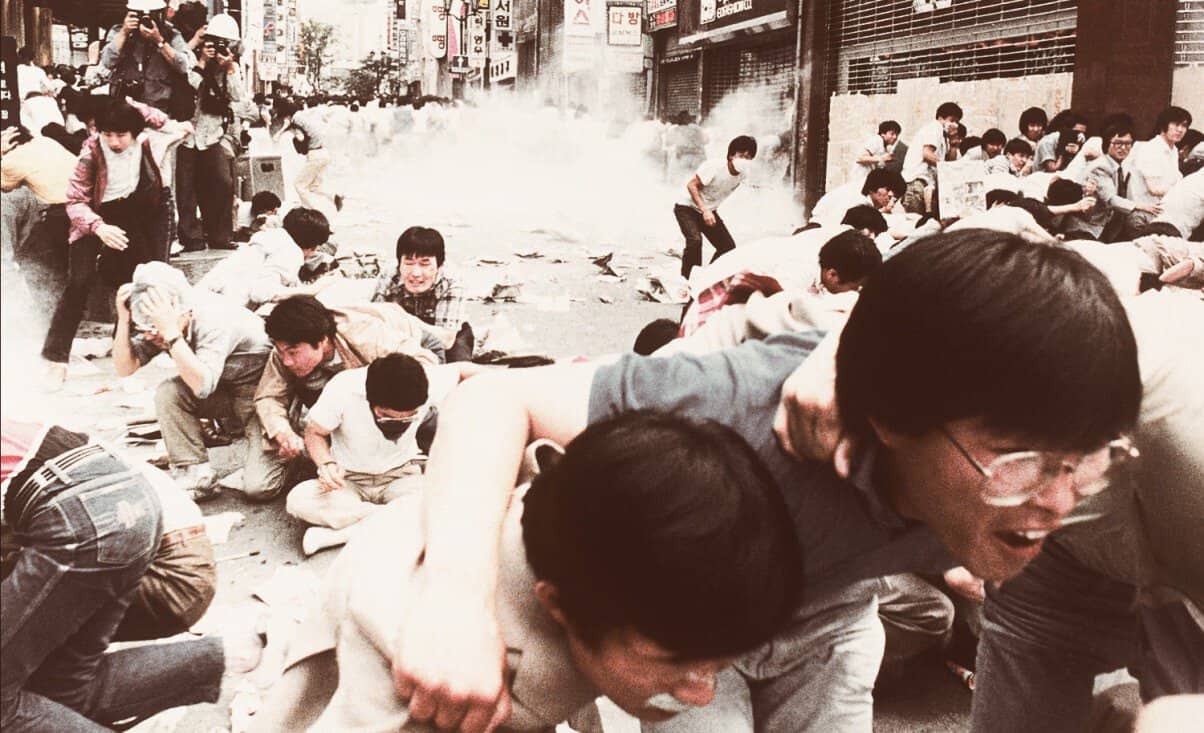 Chaos and tear gas during the 1980 Gwangju Uprising in South Korea, captured in a historic image of civilians and protesters fighting for democracy.
