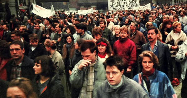 Crowd protest with diverse individuals holding signs during a demonstration, capturing a moment of political activism and social movement history from the 1980s or 1990s.