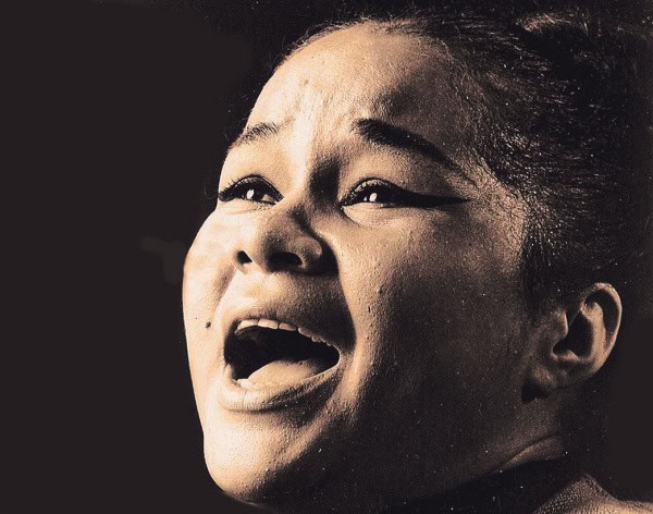 Close-up of a woman singing passionately, capturing raw emotion and powerful vocal expression.