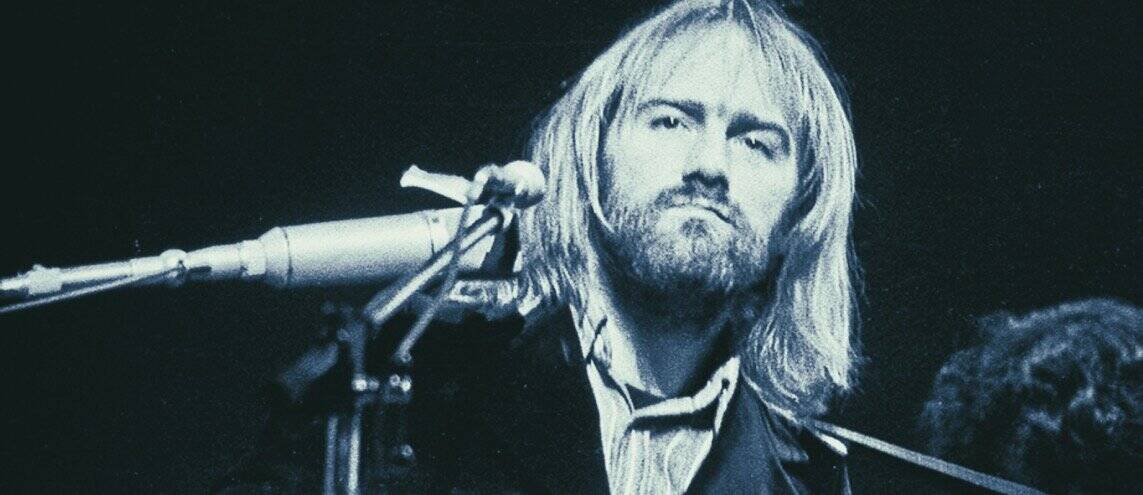 Richie Furey with long blonde hair and beard performing at a historic music event, representing iconic figures in music history.