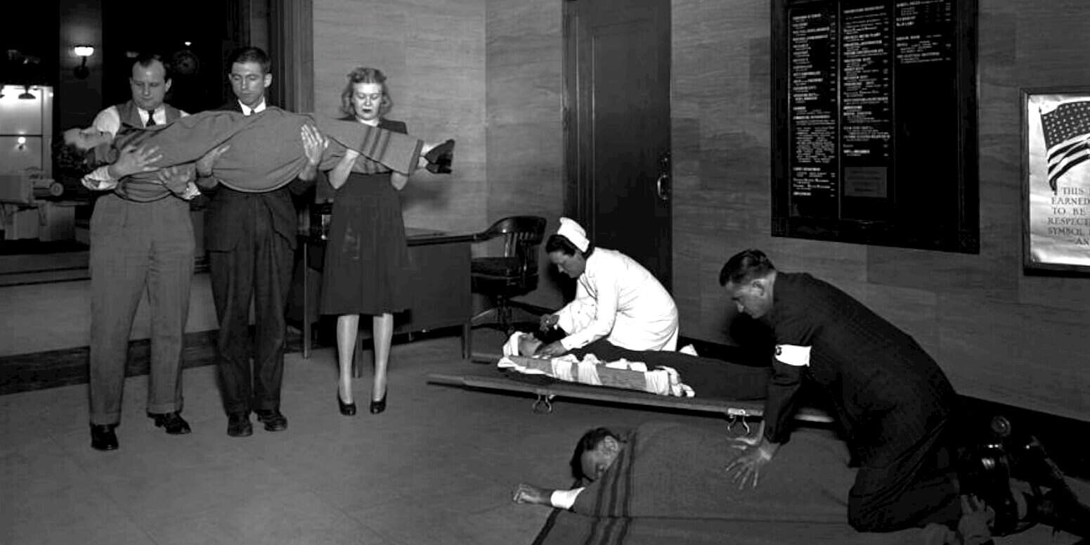 Suspicious activity in a public building with a nurse and security personnel attending to a man on the ground, hinting at a possible emergency or security incident, preserved in black and white.
