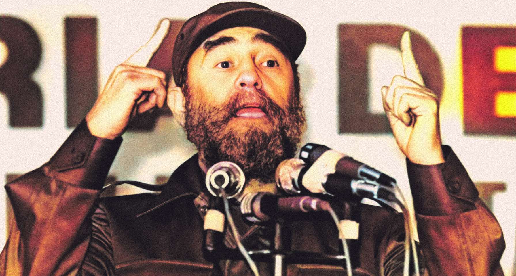 Brother Ali speaking at a press conference with microphones, representing the history and music archive of Past Daily.