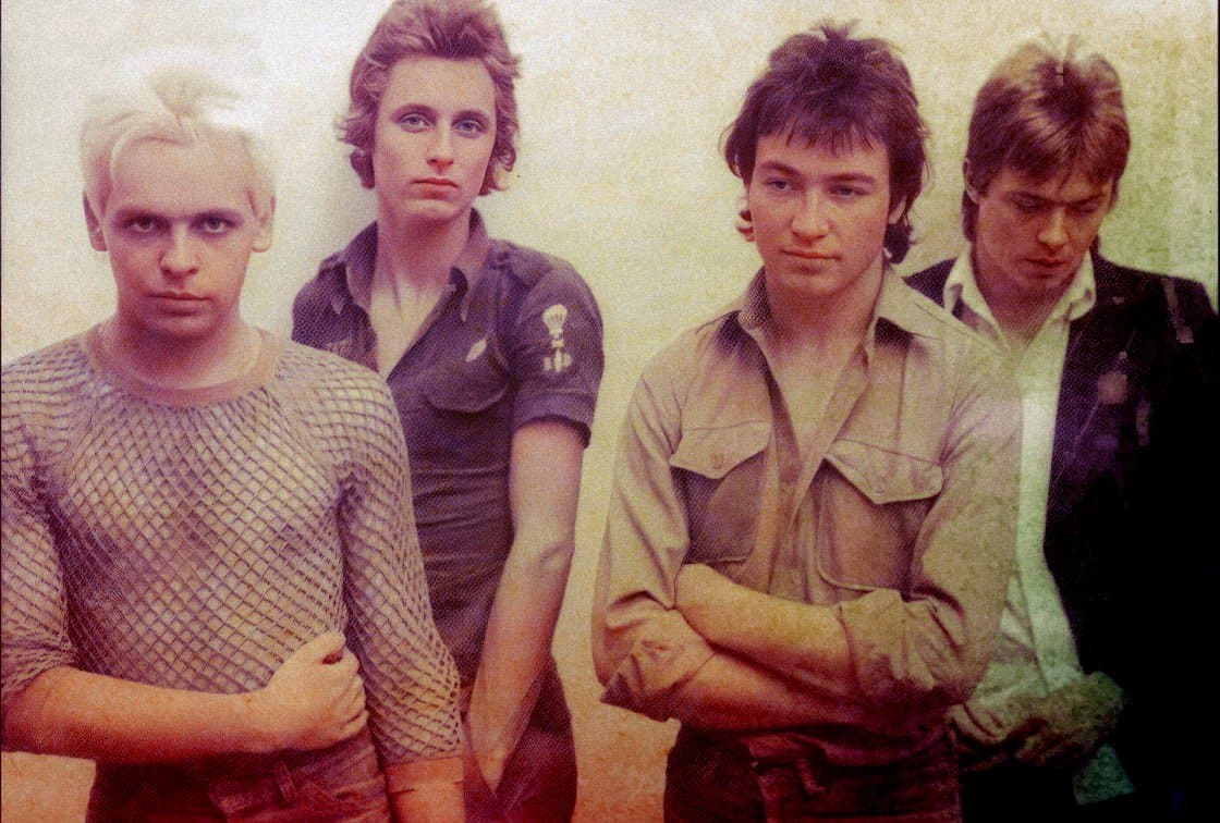 Rare vintage photograph of iconic 1980s band members with edgy fashion, symbolizing music history and cultural influence. Perfect for nostalgia and music archive collections.