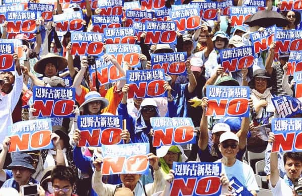 Protesters holding signs that say "NO" in a demonstration against a political or environmental issue, showcasing active public resistance and community activism.