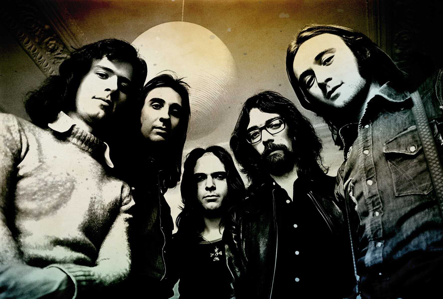 Vintage rock band photo in black and white, showcasing musicians with long hair and casual jackets, emphasizing classic music history and sound archive relevance.