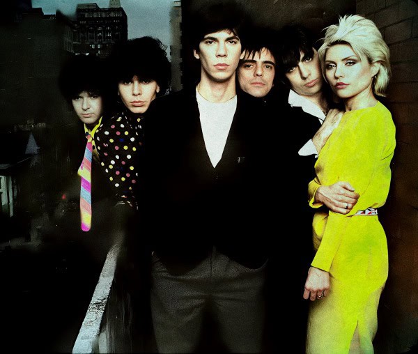 1980s new wave band The Bangles, known for their hit songs and retro style, standing outdoors in stylish clothing with cityscape background, capturing the vibrant music and pop culture of the era.