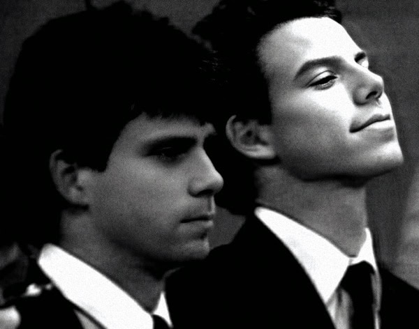 Young men in formal suits, black-and-white photograph, classic style, vintage fashion, stylish duo, timeless elegance, formal event, sophisticated look, nostalgic image, past daily archive.