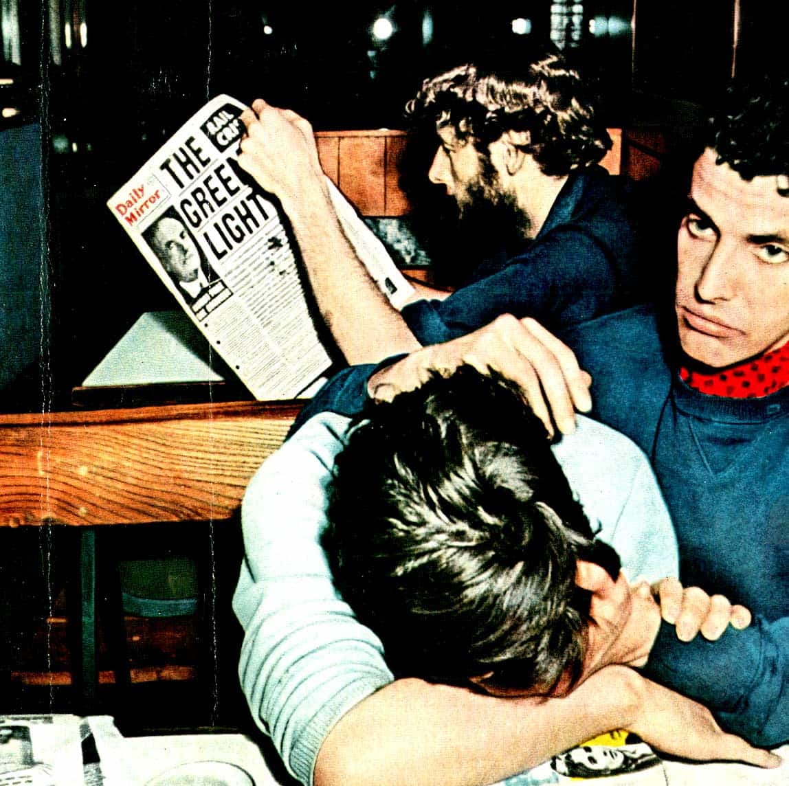 "Young men fighting in a diner, one with a newspaper, depicting a moment of conflict or tension.".