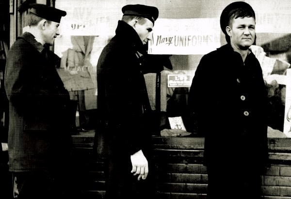 Teenagers protesting with signs about mandatory uniforms in a black and white historical image, capturing student activism and social movements from the past.