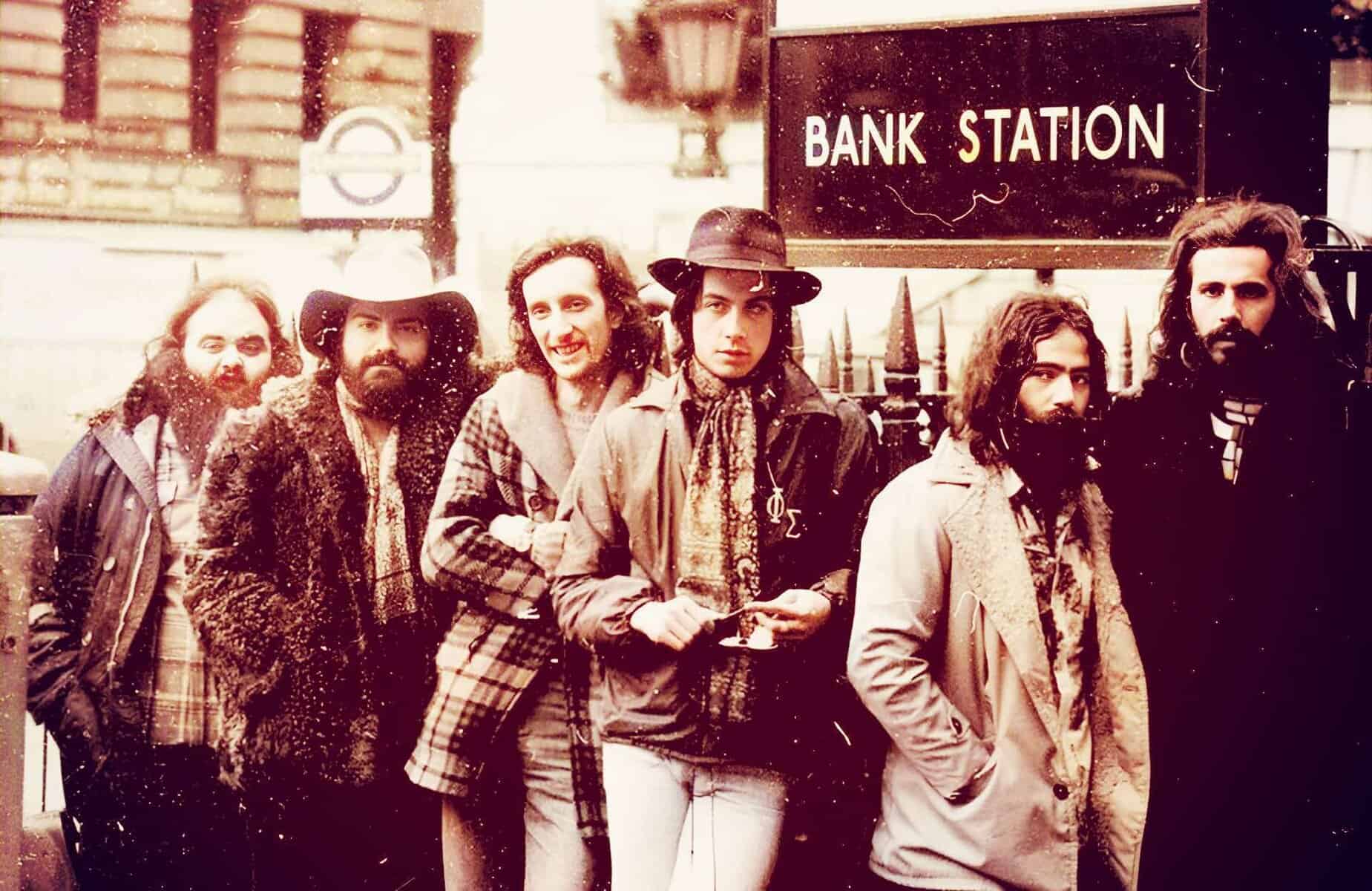 A vintage photo of a group of six people waiting at a bank station, capturing a retro atmosphere with 1970s fashion and style, emphasizing the historic music and news era.