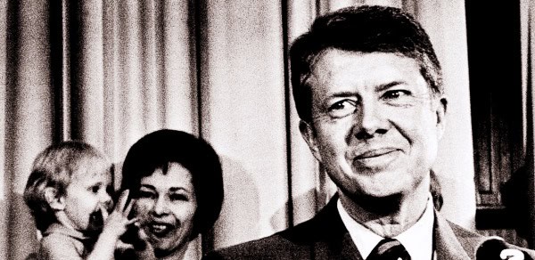 Vintage black and white photo of John F. Kennedy smiling, with Jacqueline Kennedy and a young child, capturing an iconic moment in American political history and presidential legacy.