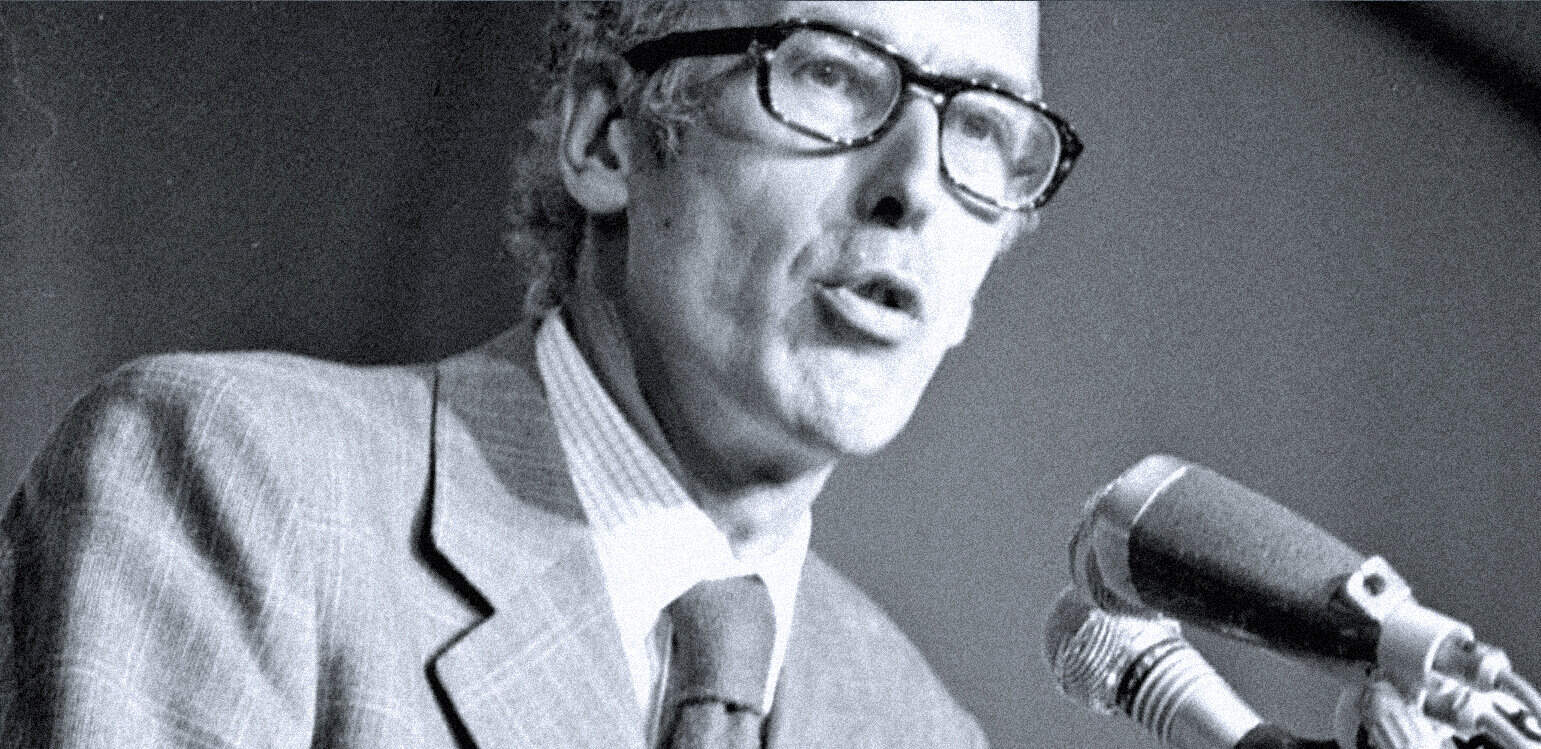 Historical radio broadcaster speaking into microphone, vintage news and music archive, black and white image of a man in glasses, representing Past Daily sound archive of news, history, and music.