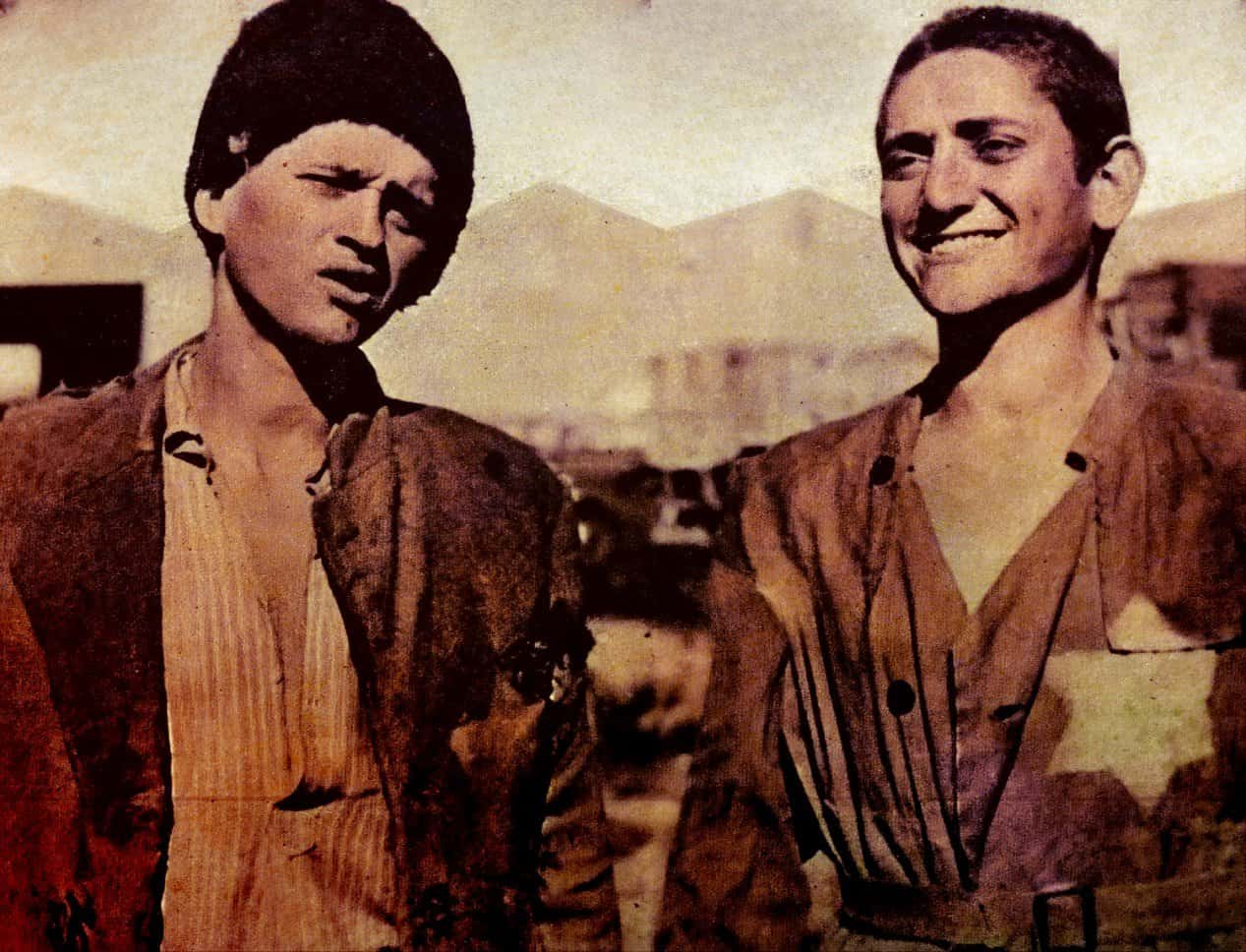 A vintage photo of two men with contrasting expressions, set against a desert landscape, capturing historical moments and cultural significance in news, history, and music archives.