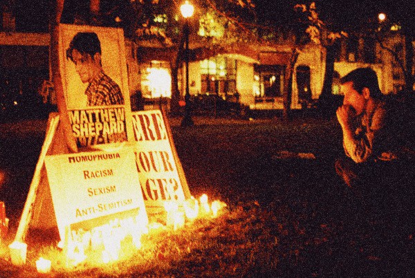 Matt Shepard memorial with candles and protest signs highlighting issues like racism, sexism, and anti-Semitism, reflecting historical social activism and community remembrance.