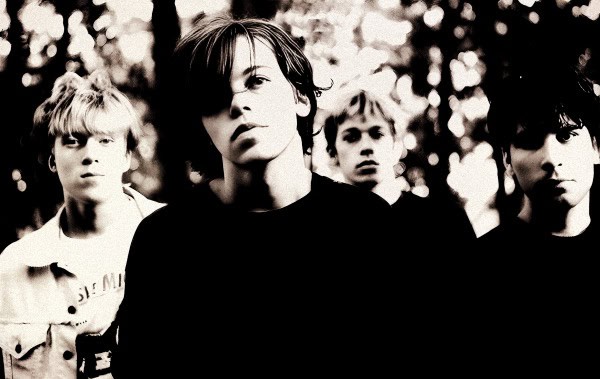 A black and white image of a band with four members, highlighting vintage music photography and historical sound archives.