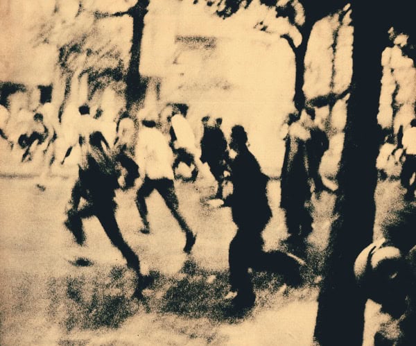 People dancing outdoors in a historical black-and-white photograph, capturing a lively moment of community and culture from past news and history archives.