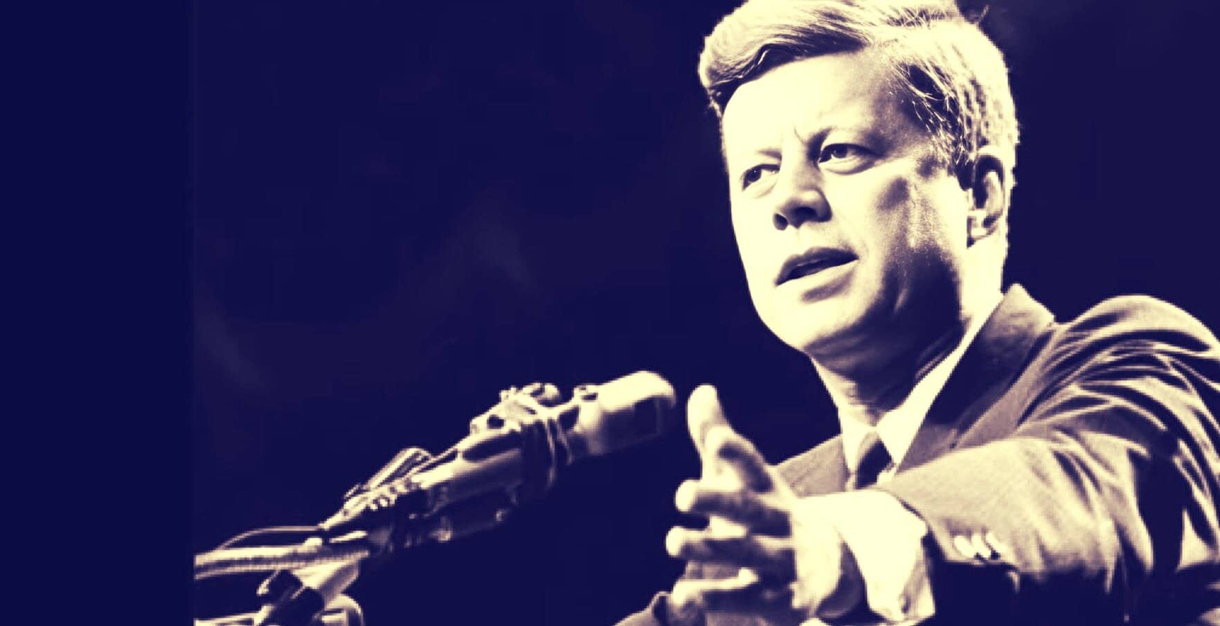 A black and white photo of John F. Kennedy speaking at a speech with hand gestures. Historic political speech image emphasizing news, history, and leadership.