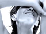 Close-up of a woman smiling with her arm resting across her face, black and white photo, capturing emotion and human expression, suitable for news, history, and music archive contexts.
