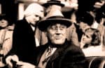 Old black and white photo of a man wearing a hat, surrounded by people, capturing a historic moment related to news, history, and music archives.
