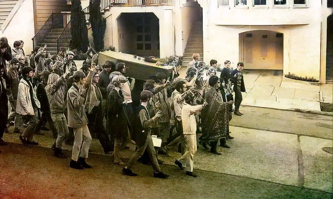 Grieving process of a funeral procession with a coffin carried by pallbearers and mourners walking in a somber procession outside an urban building, capturing a moment of grief and tribute.