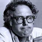 Black and white portrait of a man with curly hair and glasses, representing a figure from historical audio archives related to news, music, and cultural history.