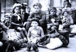 Desperate children refugees at a historic refugee camp, emphasizing the impact of war and displacement, with vintage attire and packed luggage for migration or resettlement.