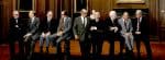 Former US presidents sitting on a bench in a historic wooden-paneled room during a meeting or discussion about American history and politics.