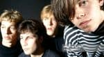 Teenage boys with 1960s rock band style, musician portrait, casual clothing, close-up of faces, artistic group photo, band members, concert, music history, youth culture, band photography, black background, vintage vibe, popular music, artist promotional image, album cover, concert poster relevance.