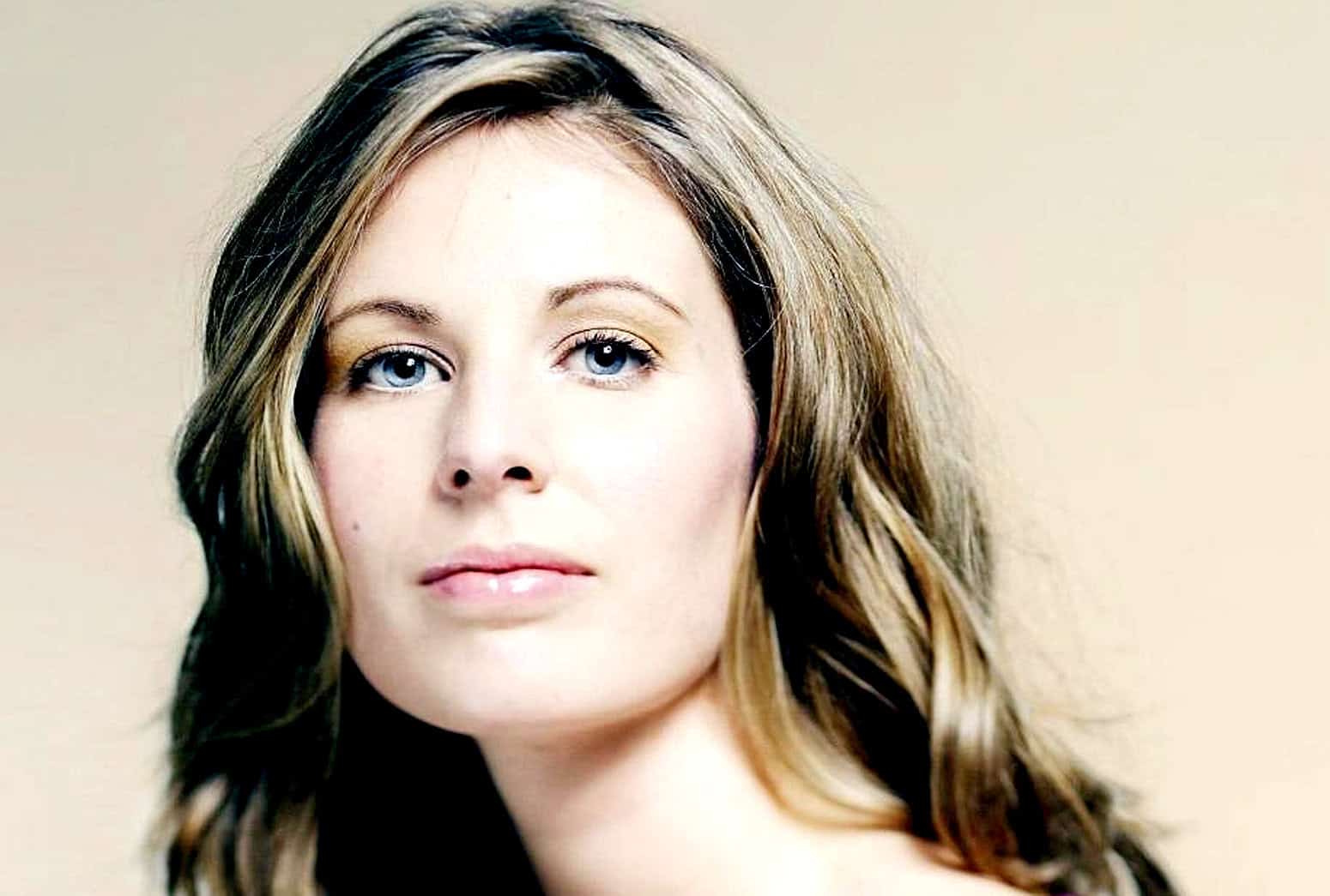 Stunning woman with blue eyes and wavy brown hair, portrait for music, history, and news archives, representing Past Daily's sound archive of news, music, and history.