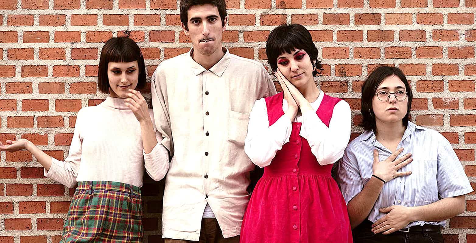 People standing against a brick wall, diverse young adults, casual clothing, modern fashion, expressive poses, urban setting, group photo, lifestyle imagery, young generation, contemporary style.