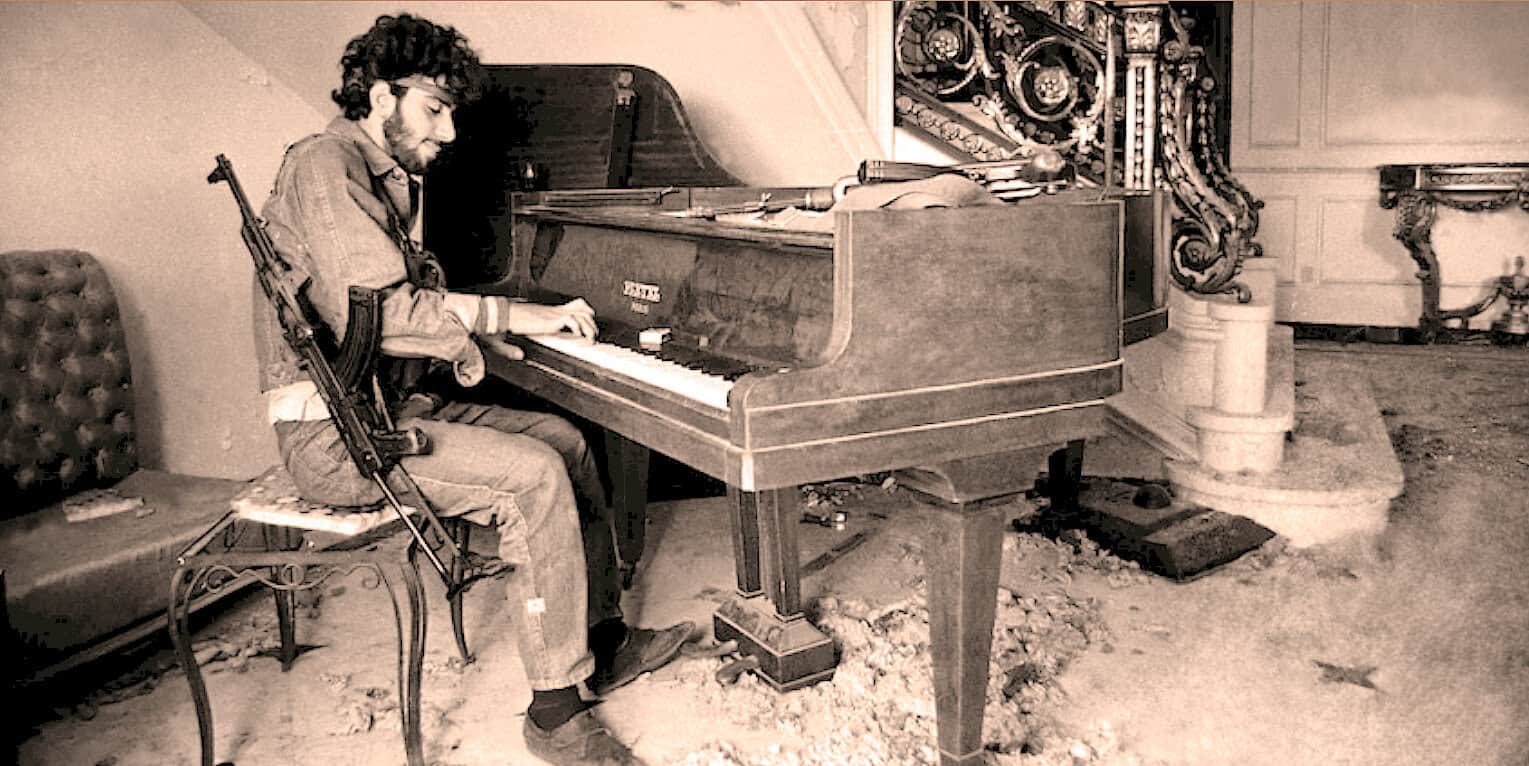 A young man with a rifle sitting at a grand piano in a vintage, ornate room, capturing a blend of music and historical or documentary themes.