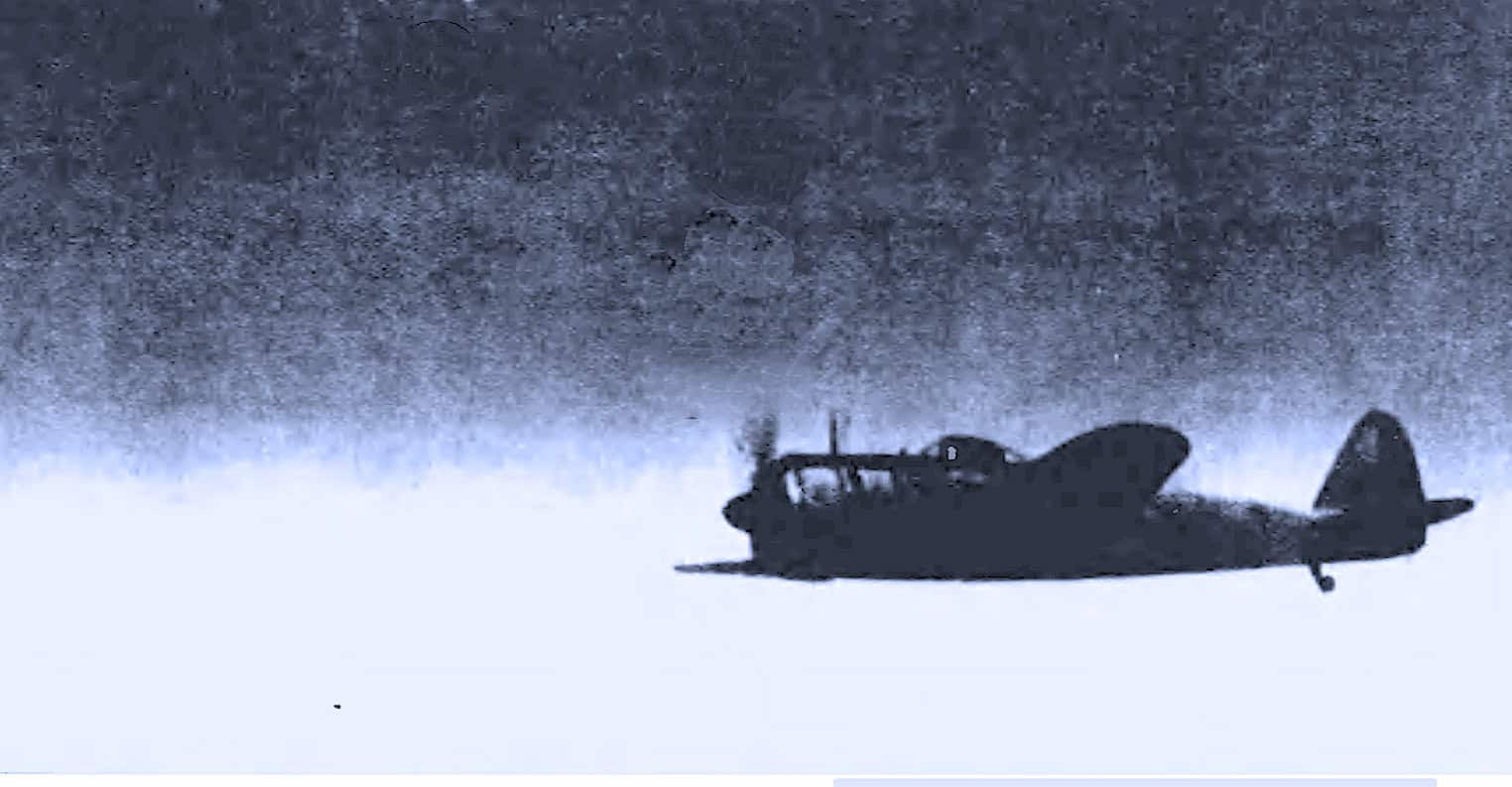 An upside-down silhouette of a vintage military aircraft flying low over a cloudy sky, capturing a historic moment in aviation history.