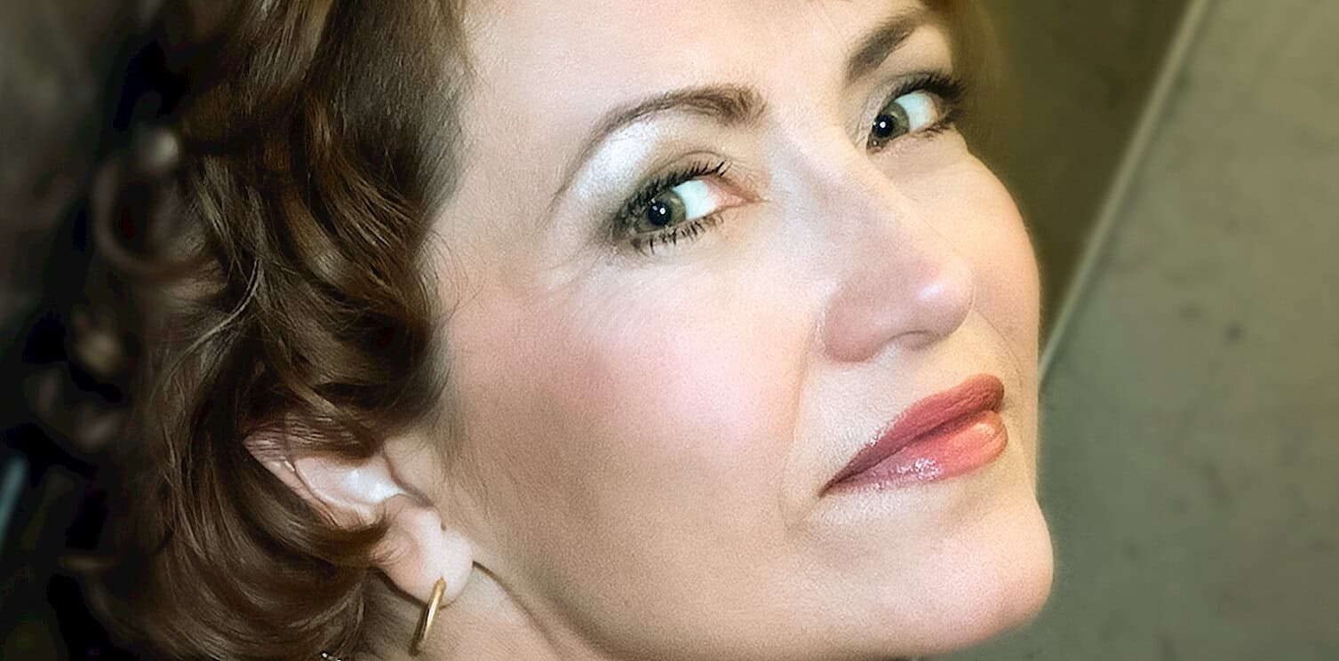 Close-up portrait of a woman with vintage style makeup, curled hair, and elegant appearance; representing classic beauty and timeless fashion in news, history, and music archives.