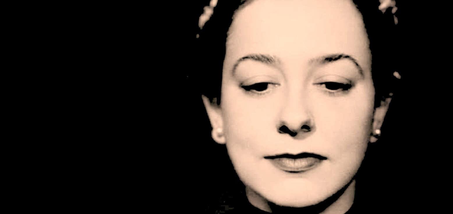 Vintage black and white photo of a woman with elegant makeup and pearl earrings, representing a classic era of news, history, and music archives.