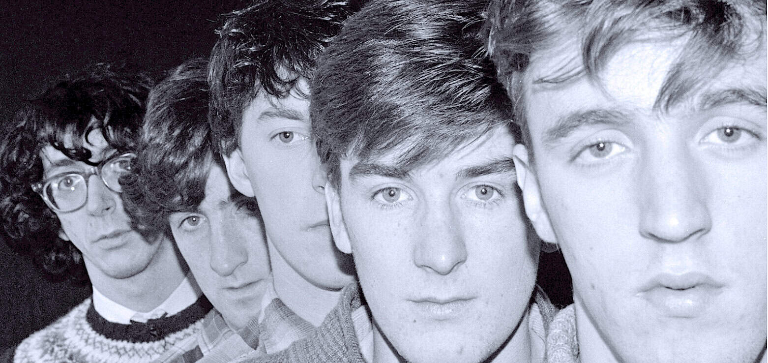A black-and-white photo of The Beatles, showcasing their iconic youthful faces and hairstyles, representing music history, news archives, and cultural influence.