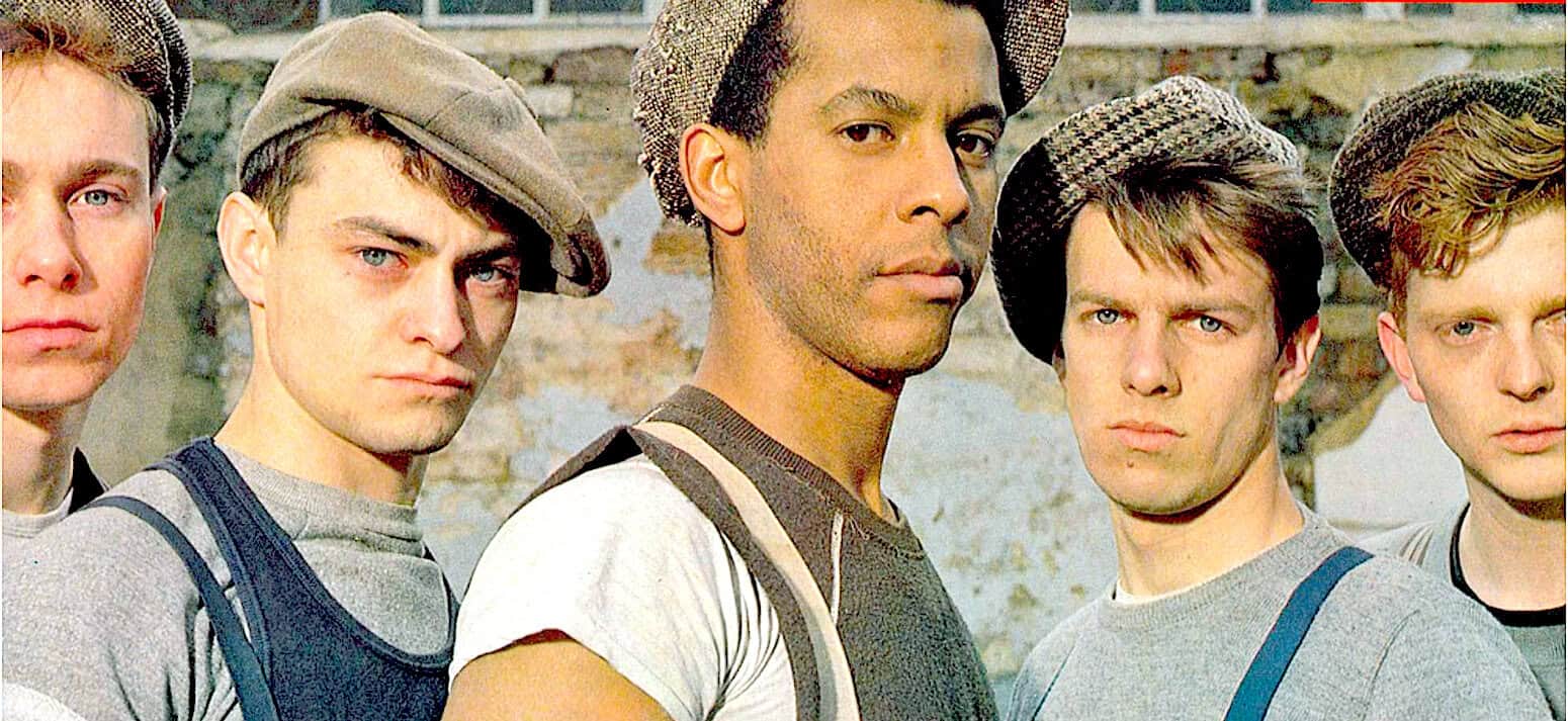 Historical film scene featuring young men in 1940s military attire, emphasizing wartime youth and camaraderie, ideal for news, history, and music archives on pastdaily.com.