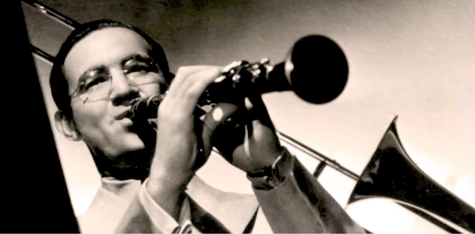 Vintage black and white photo of a man playing the trumpet with headphones, capturing historic jazz or news recording session, emphasizing archival music, history, and sound archive relevance.