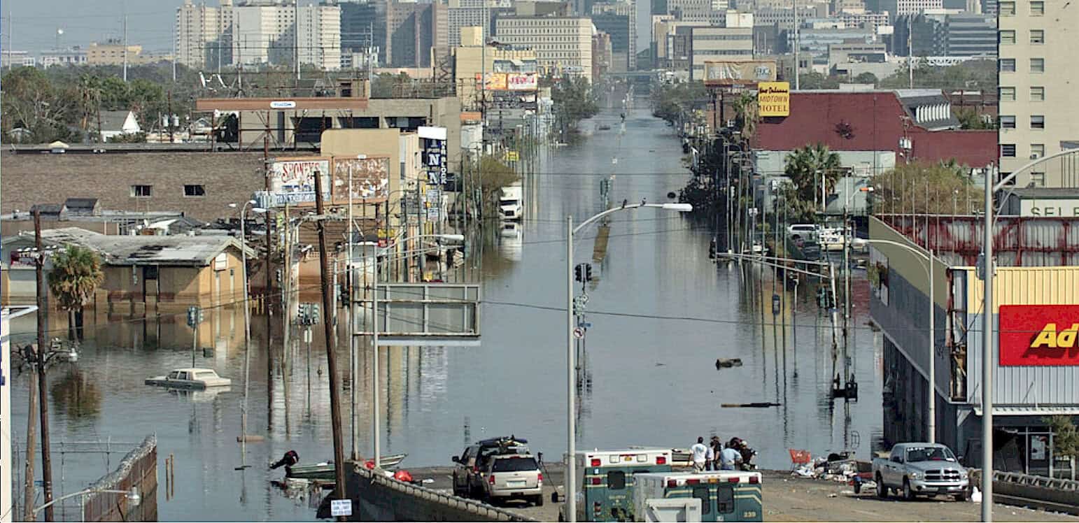 Flooded urban street after disaster, city infrastructure submerged, emergency response vehicles, severe flooding, natural disaster impact on city life.