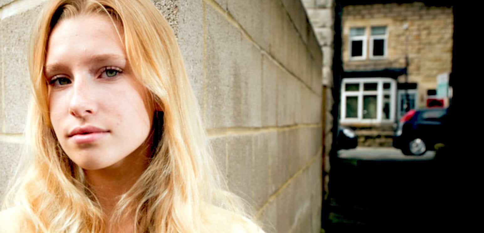 Bright portrait of a young woman with red hair standing outdoors near a stone wall, emphasizing natural beauty and urban environment for SEO.