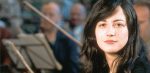 Young woman with long black hair, in a public space, representing news, history, and music archives.