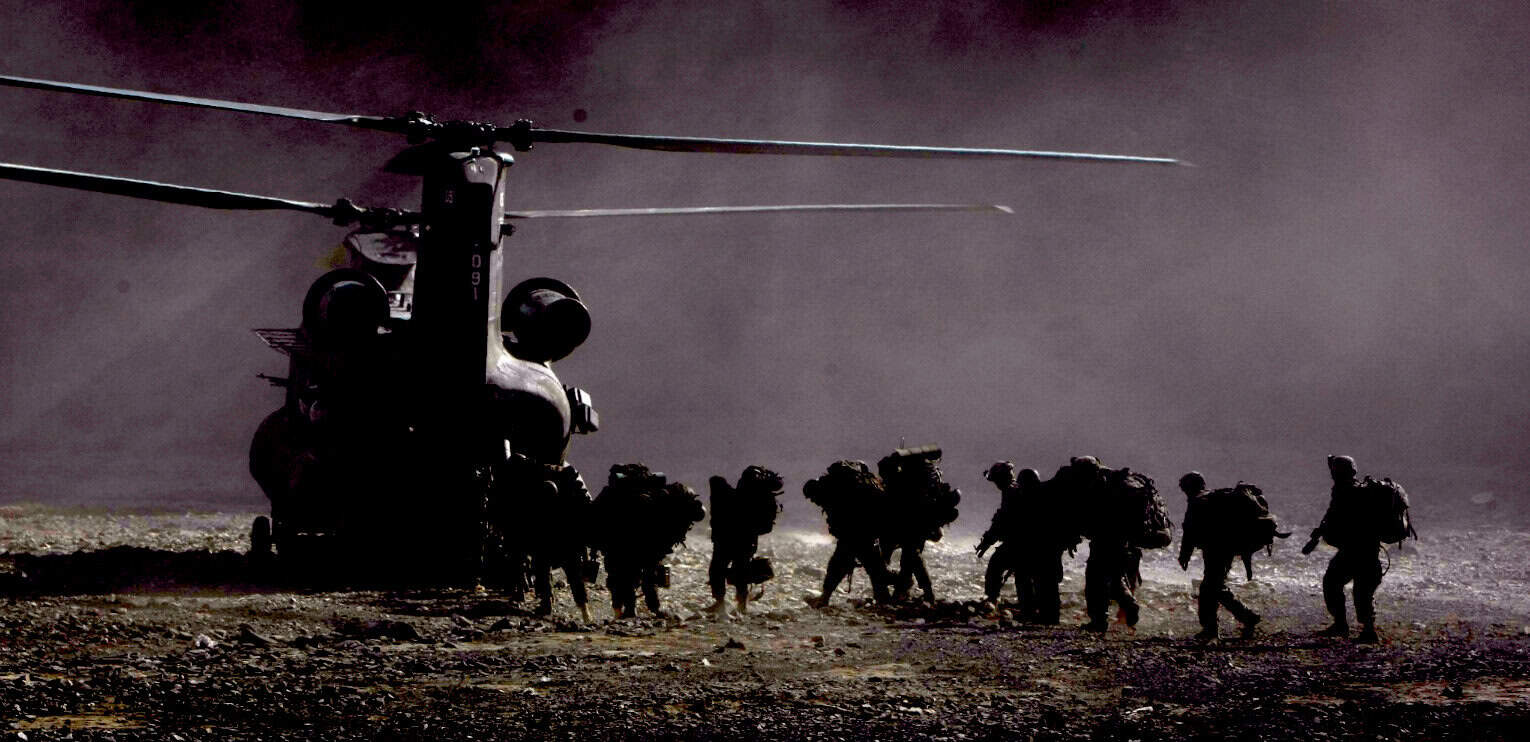 Heliopter transporting soldiers in desert terrain during dusk or dawn, military operation, armed forces, warfare, tactical helicopter, combat mission, armed personnel, military gear, training exercise, war zone.