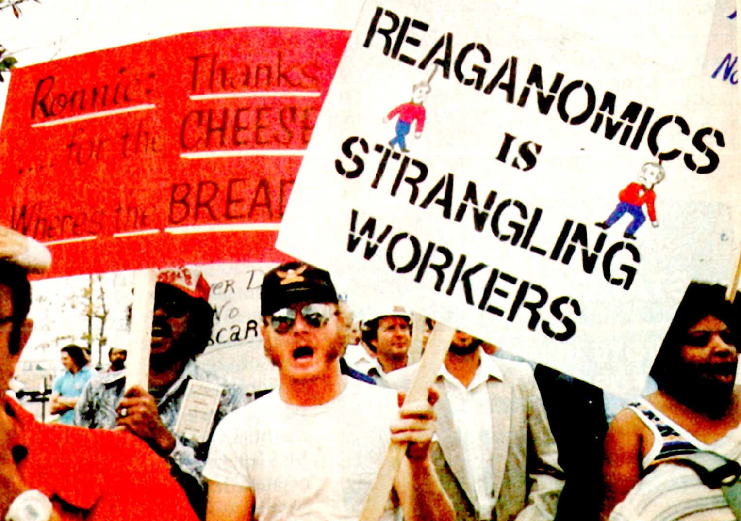 Protesters holding signs advocating workers' rights and challenging working conditions during a historical demonstration, emphasizing social activism, labor movements, and community solidarity.