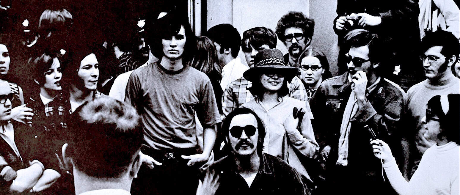 Vintage black and white photo of diverse young people socializing, capturing a cultural moment. Perfect for historical archives, music, and news history enthusiasts interested in 1960s or 1970s youth culture.