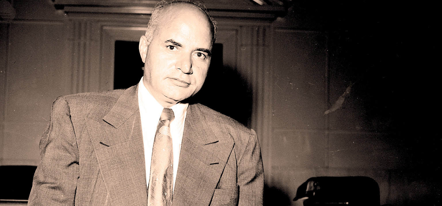 Vintage black and white photograph of a distinguished man in a suit, representing historical news, music, and archival recordings from Past Daily.